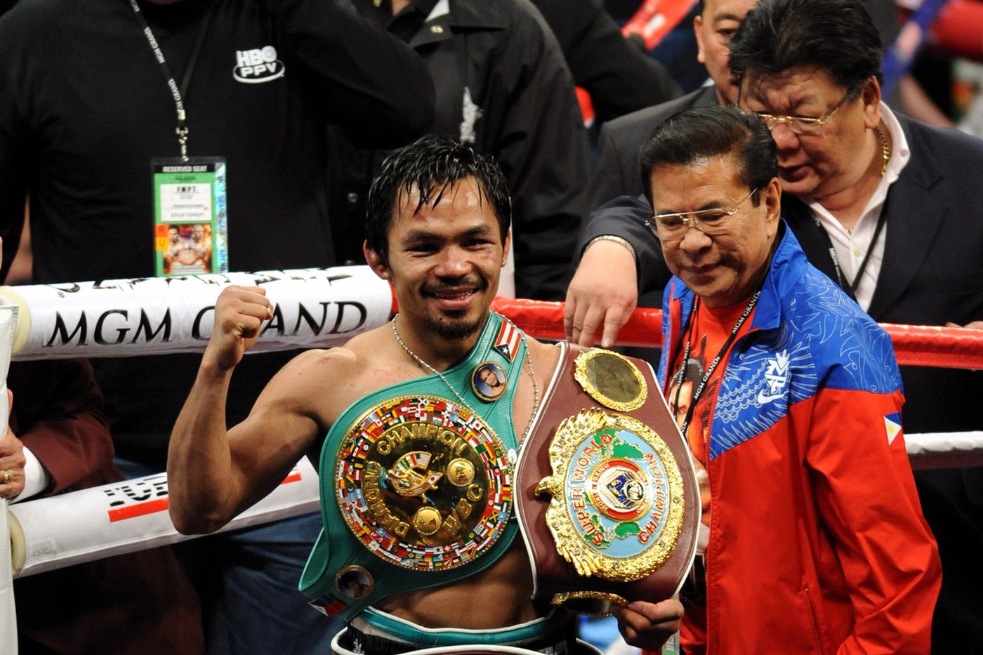 Manny Pacquiao in the ring at the MGM Grand holding three world title belts.